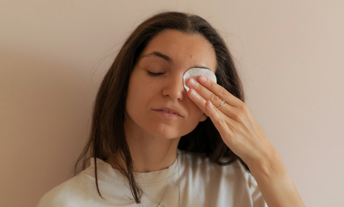 Woman with her eyes closed holding a cotton pad to one eye