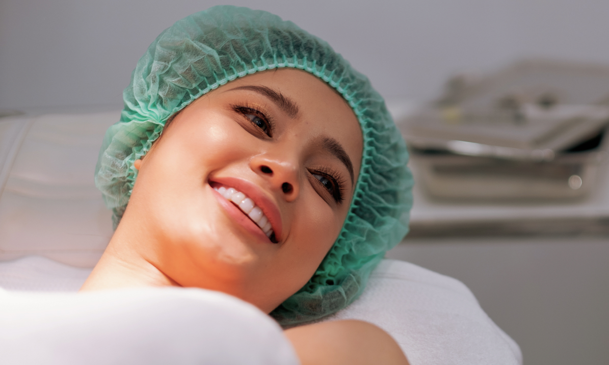 Smiling woman in a green surgical cap lying on a treatment couch