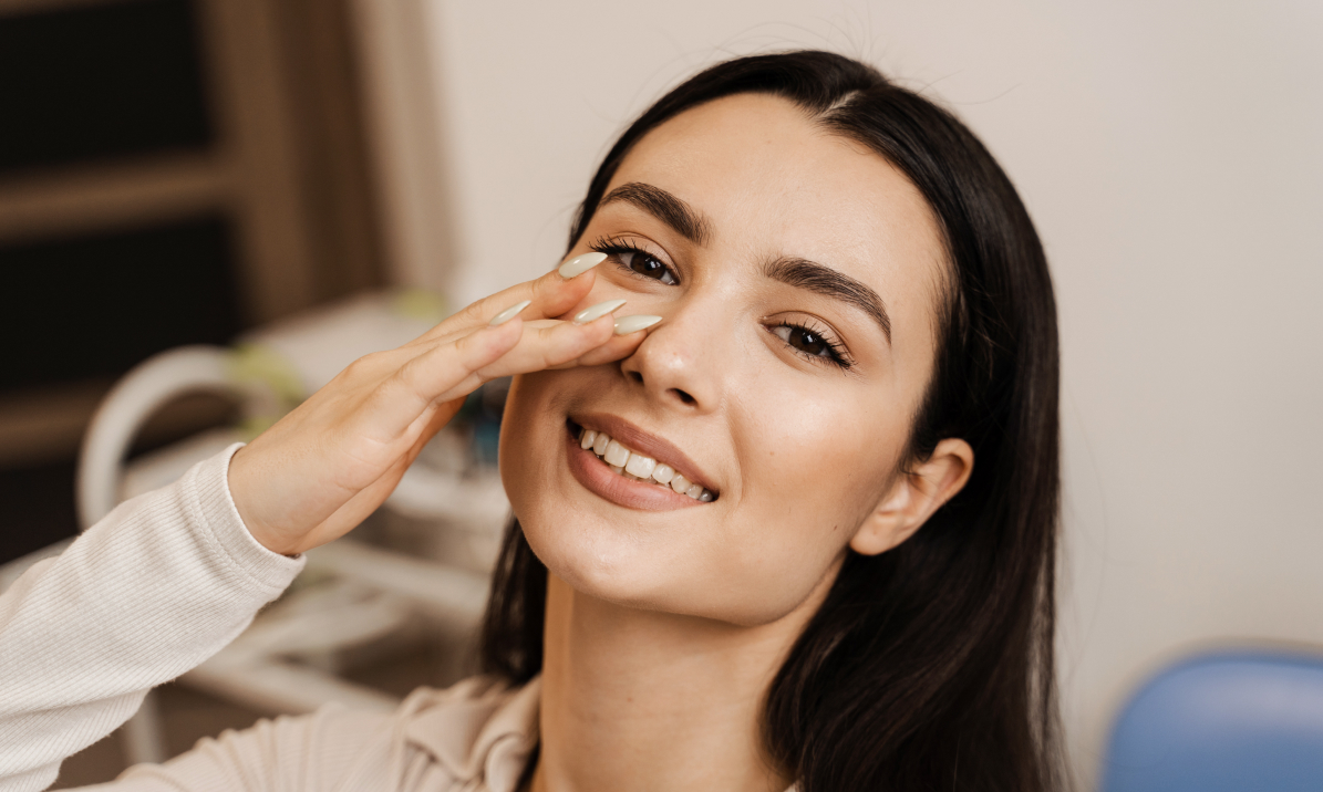 Smiling woman with dark hair resting her hand against her cheek